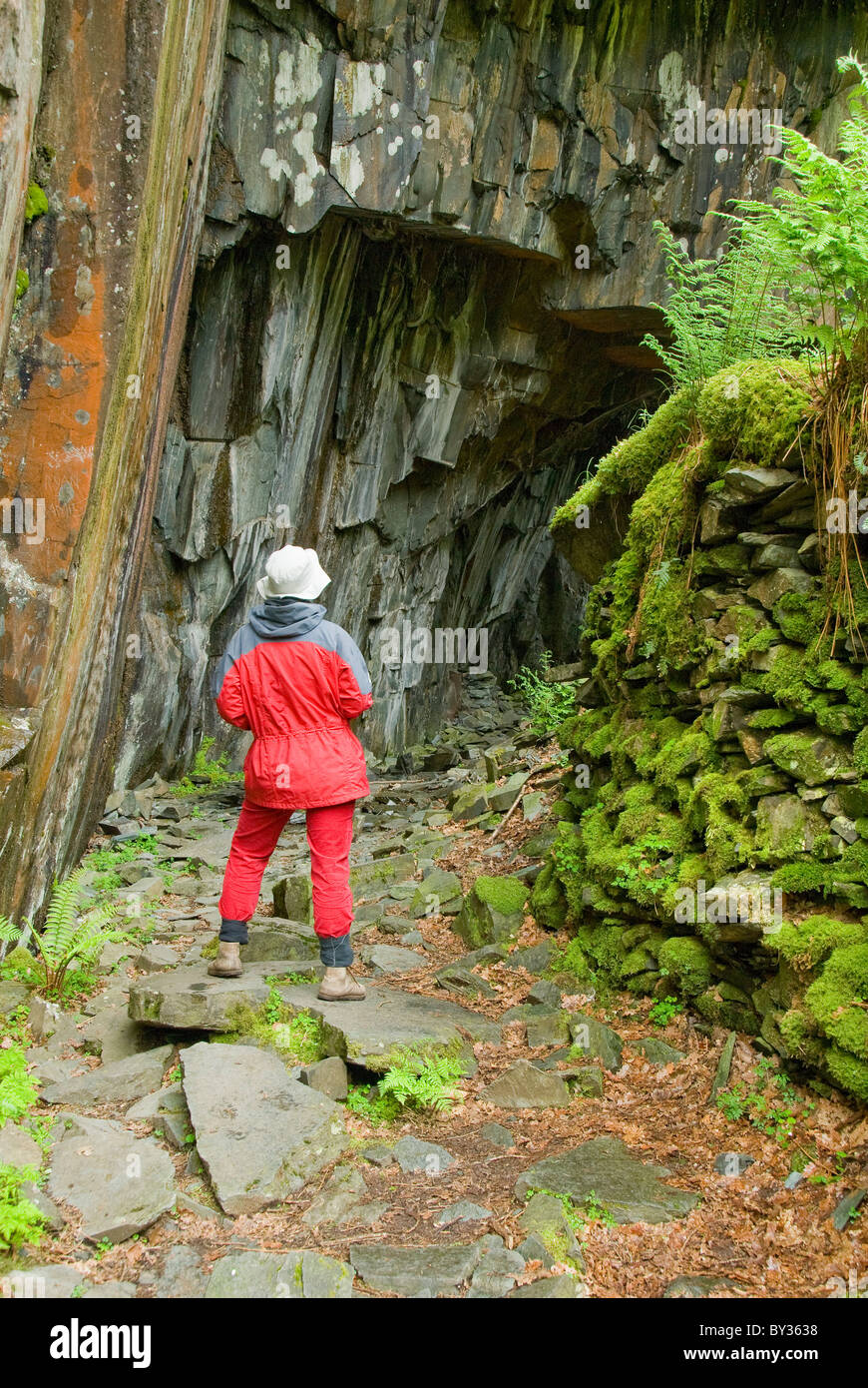 Donna in piedi all'entrata di una caverna, Parco Nazionale del Distretto dei Laghi, Cumbria, England, Regno Unito, Europa Foto Stock