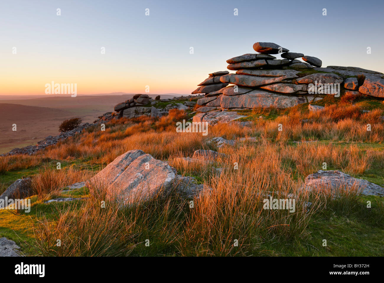 Il bagliore del sole della sera evidenzia le erbe e il promontorio roccioso di Stowe collina alta fino a Bodmin Moor. Foto Stock