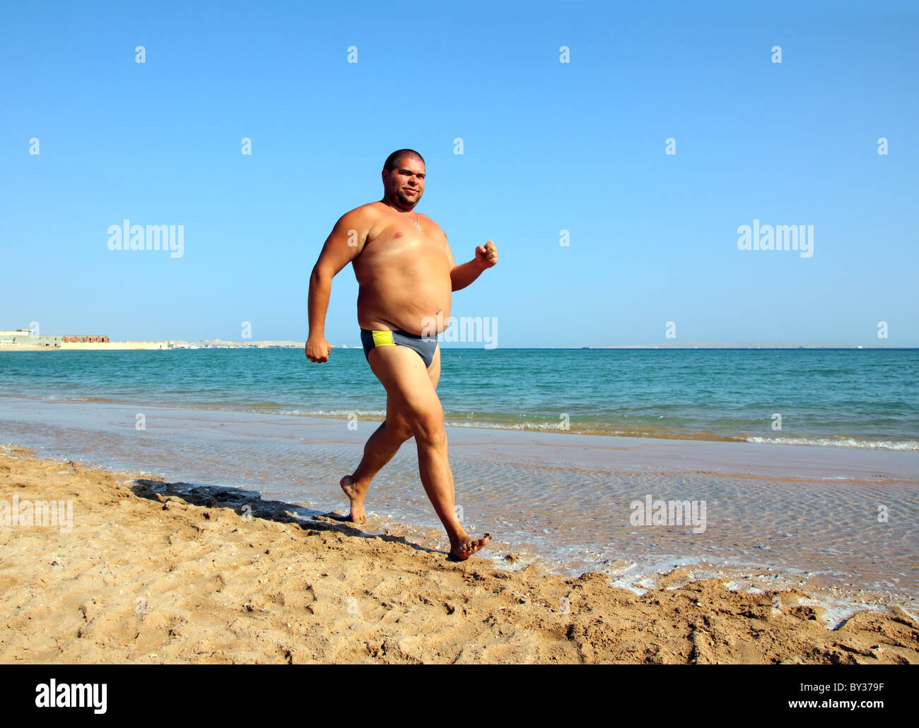 Sport - Uomo sovrappeso in esecuzione sul litorale del mare Foto Stock