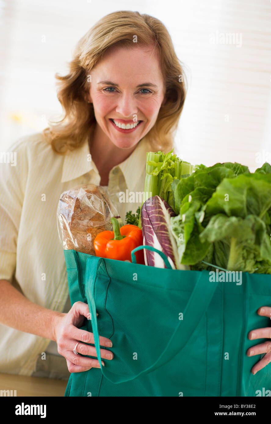 Stati Uniti d'America, New Jersey, Jersey City, ritratto di donna holding sacchetto shopper in cucina Foto Stock