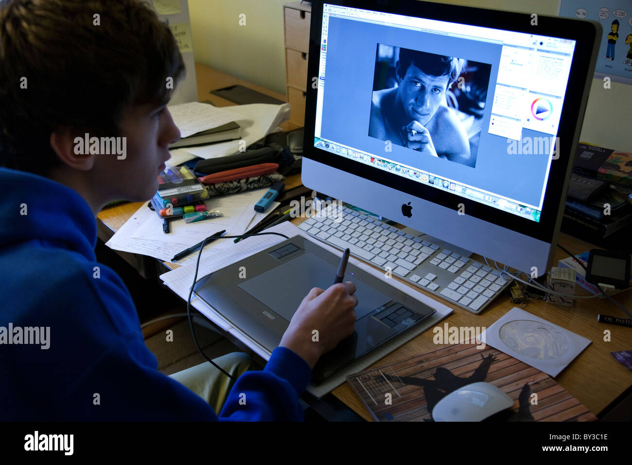 Studenti che lavorano nella sua camera da letto utilizzando una tavoletta grafica e un imac. Foto Stock