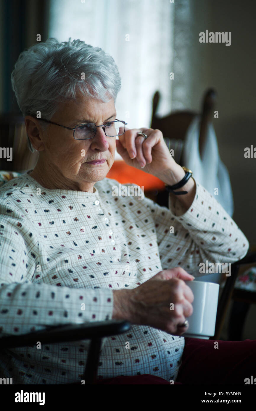 Vecchia donna con espressione preoccupata e la tazza di tè Foto Stock