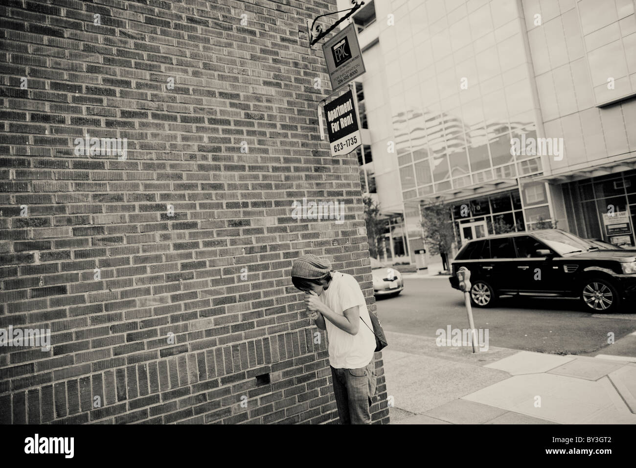 Un senzatetto giovane adulto accende una sigaretta in Downtown Seattle mentre si cammina per un senzatetto outreach center Foto Stock
