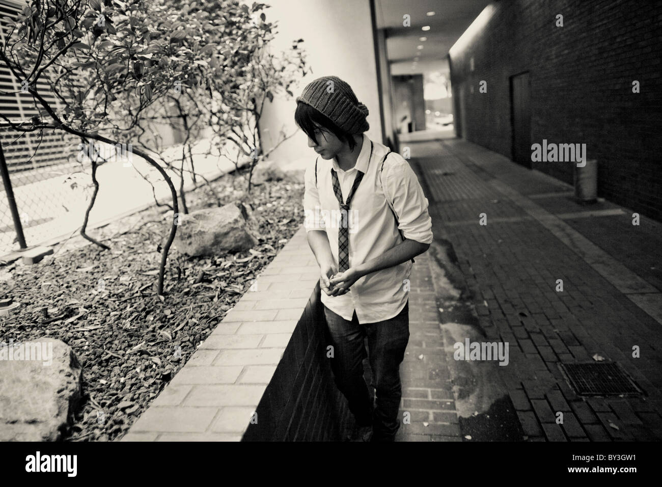 Un senzatetto giovane uomo raccoglie mozziconi di sigaretta fumare più tardi al di fuori di un edificio per uffici nel centro di Seattle Foto Stock