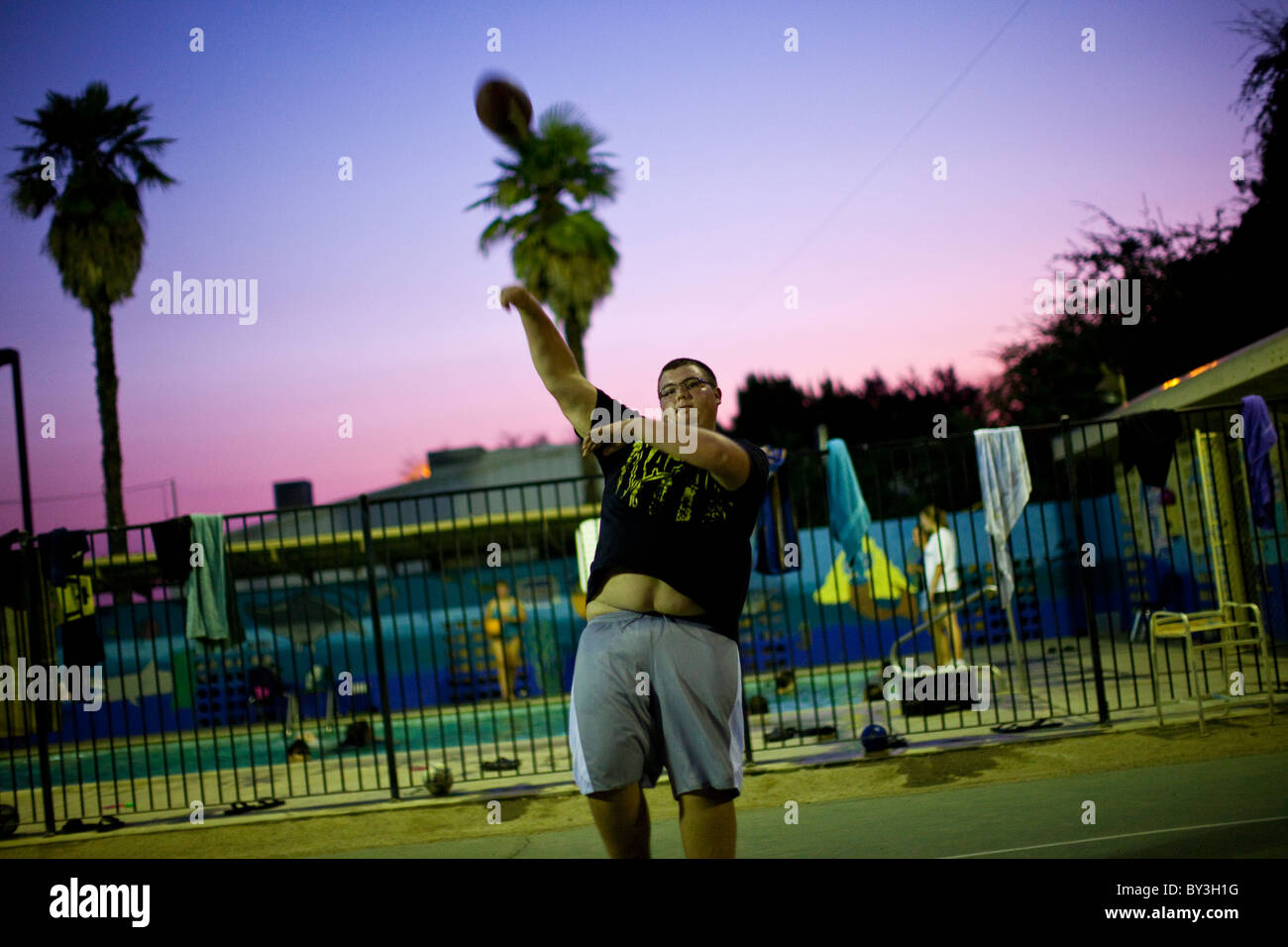 Reedley, California, Stati Uniti. Un obeso ragazzo adolescente getta il calcio al tramonto. Foto Stock