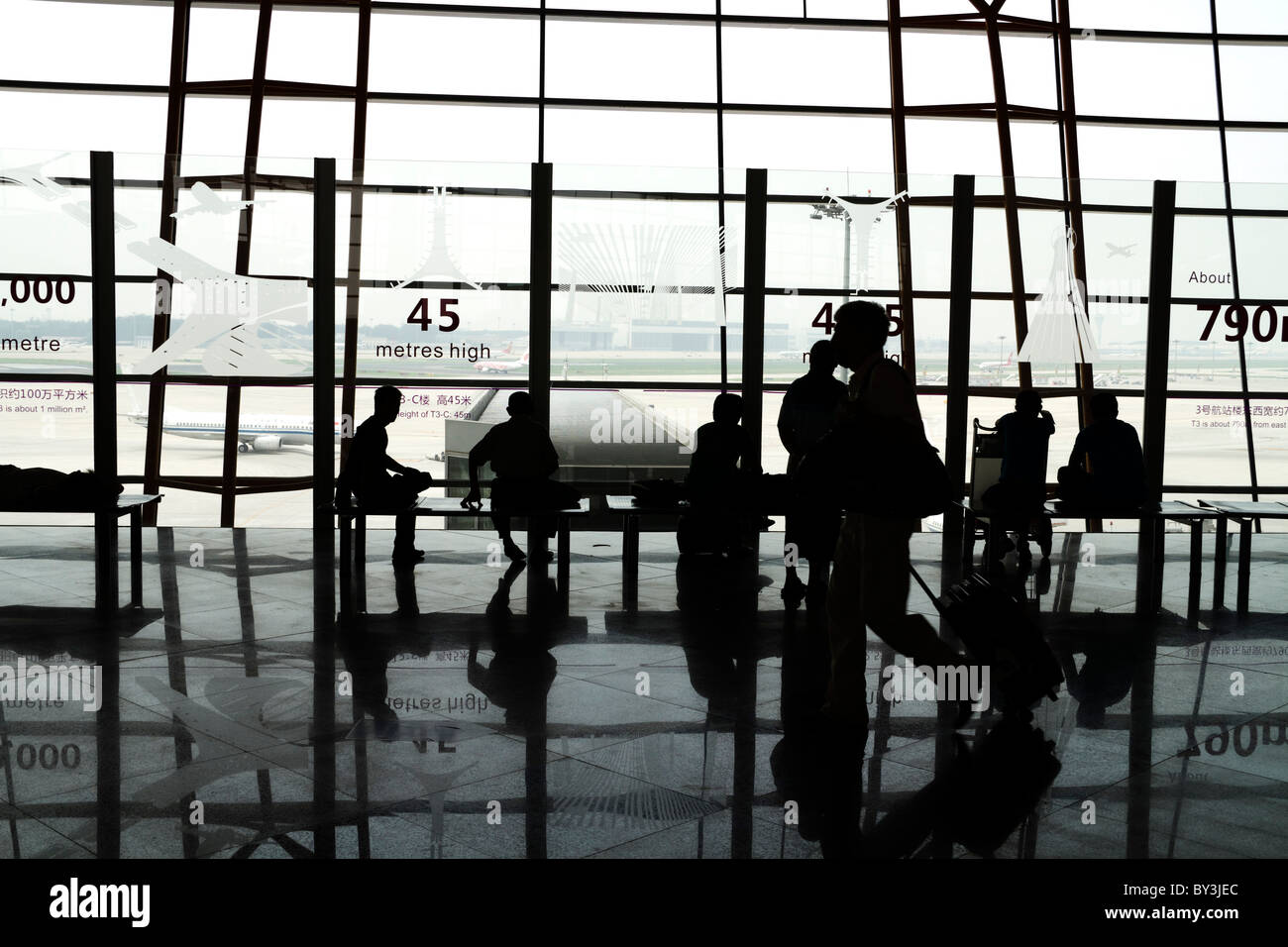 Sagome e riflessioni di passeggeri in attesa all'aeroporto di Pechino Foto Stock