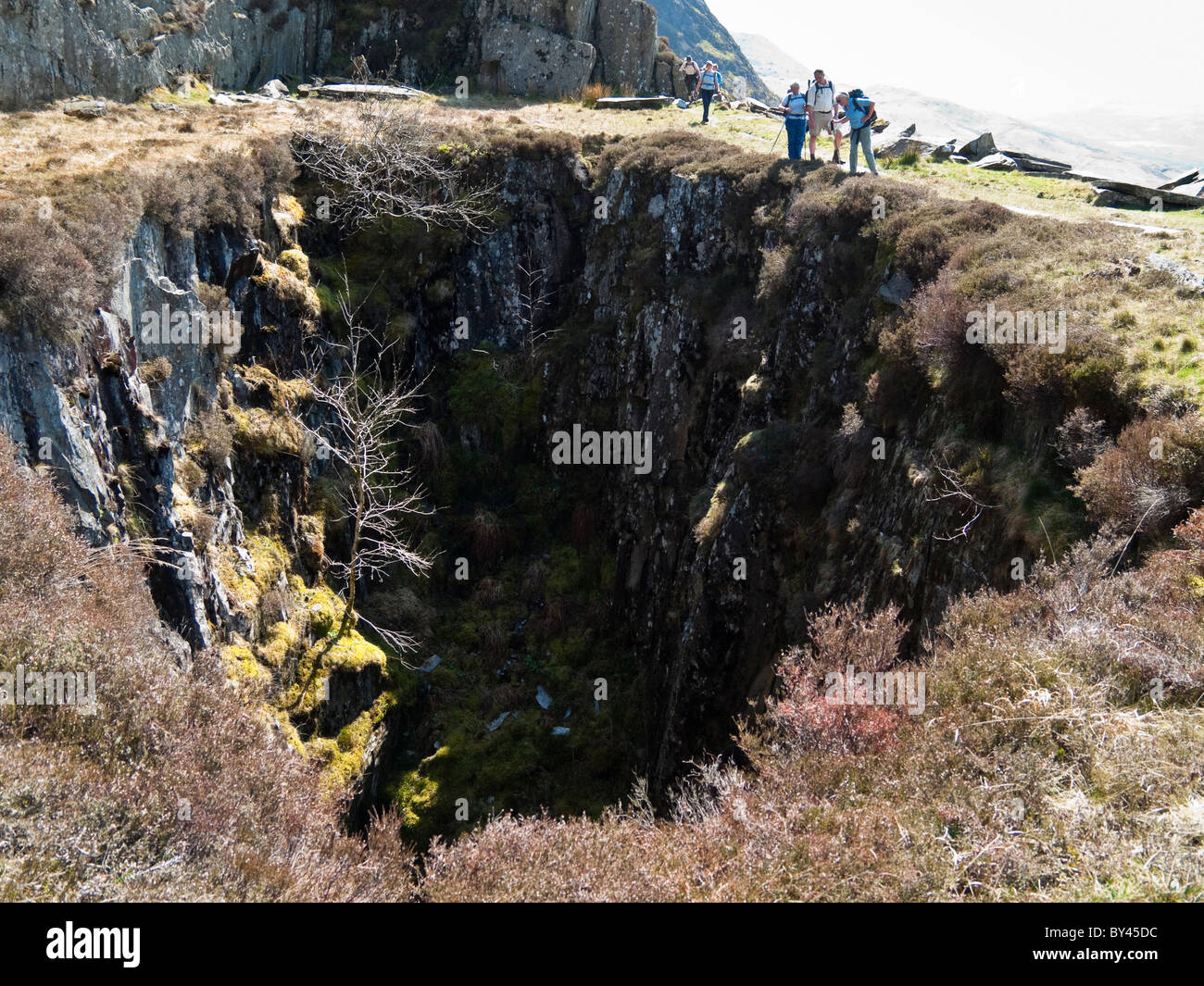 Cwm Pennant, Gwynedd, Galles del Nord, Regno Unito. Walkers da un vecchio albero di miniera in disuso cava di ardesia nel Parco Nazionale di Snowdonia Foto Stock