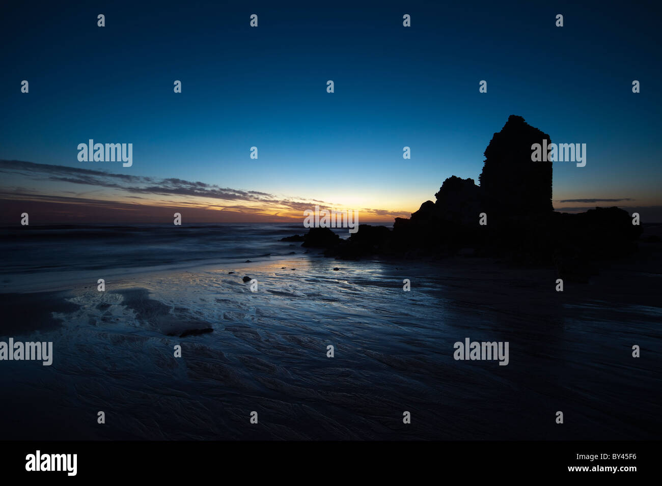 La torre in rovina sulla spiaggia al tramonto Foto Stock