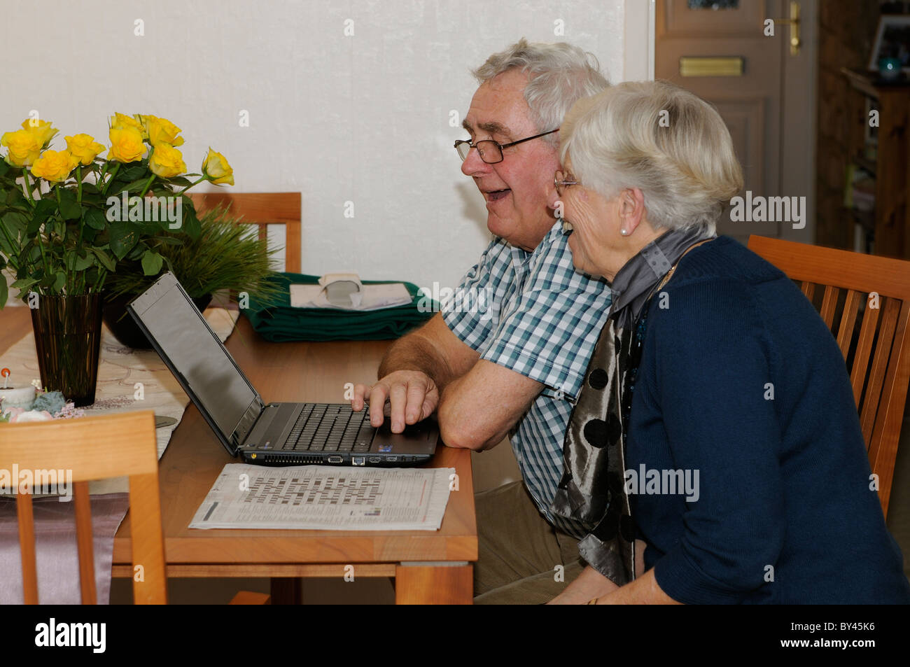 Coppia di anziani utilizzare il computer portatile per amici Skype tramite Internet da casa propria Foto Stock
