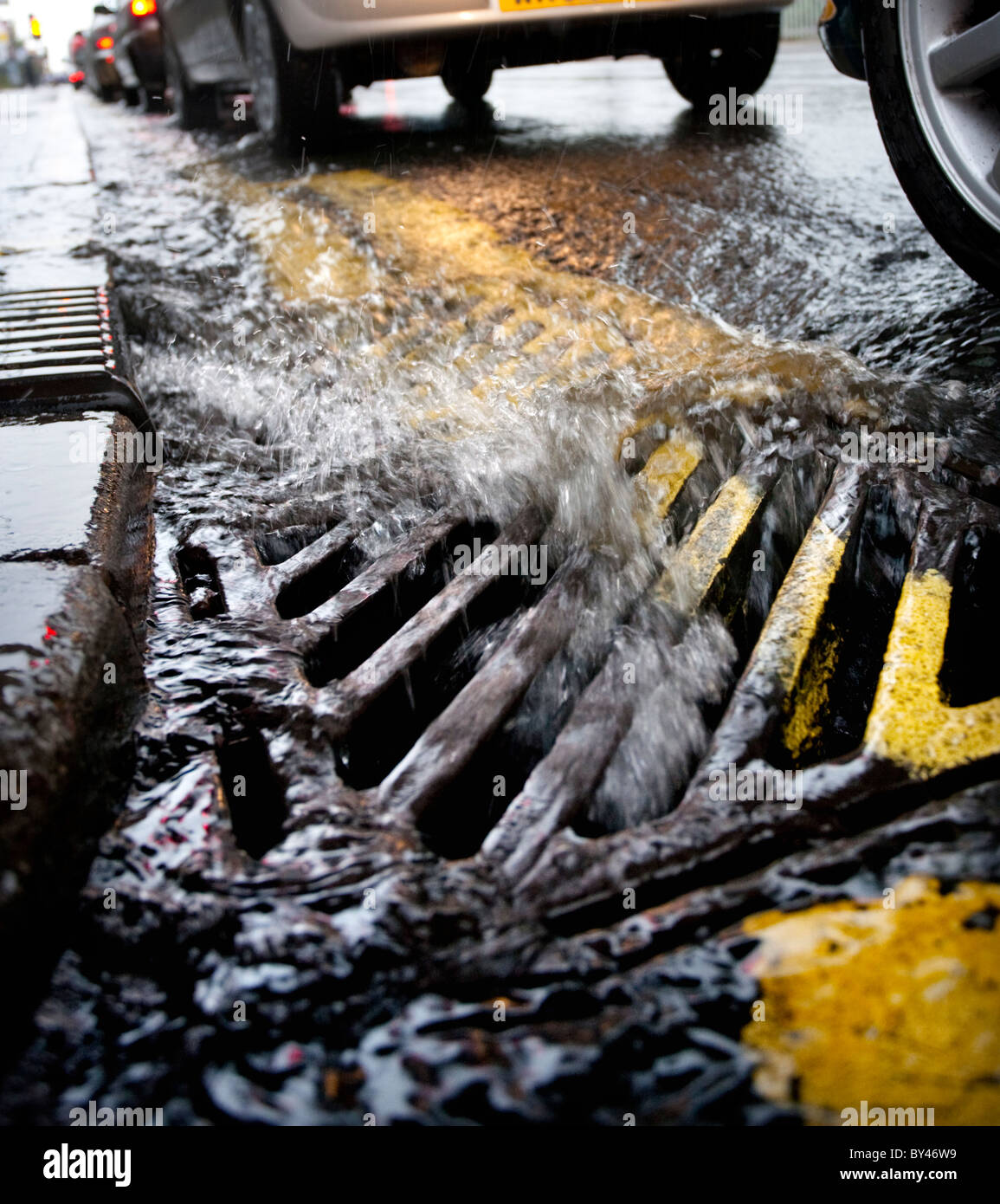 Acqua di pioggia che scorre in una griglia a lato di una strada a Birmingham, Regno Unito Foto Stock