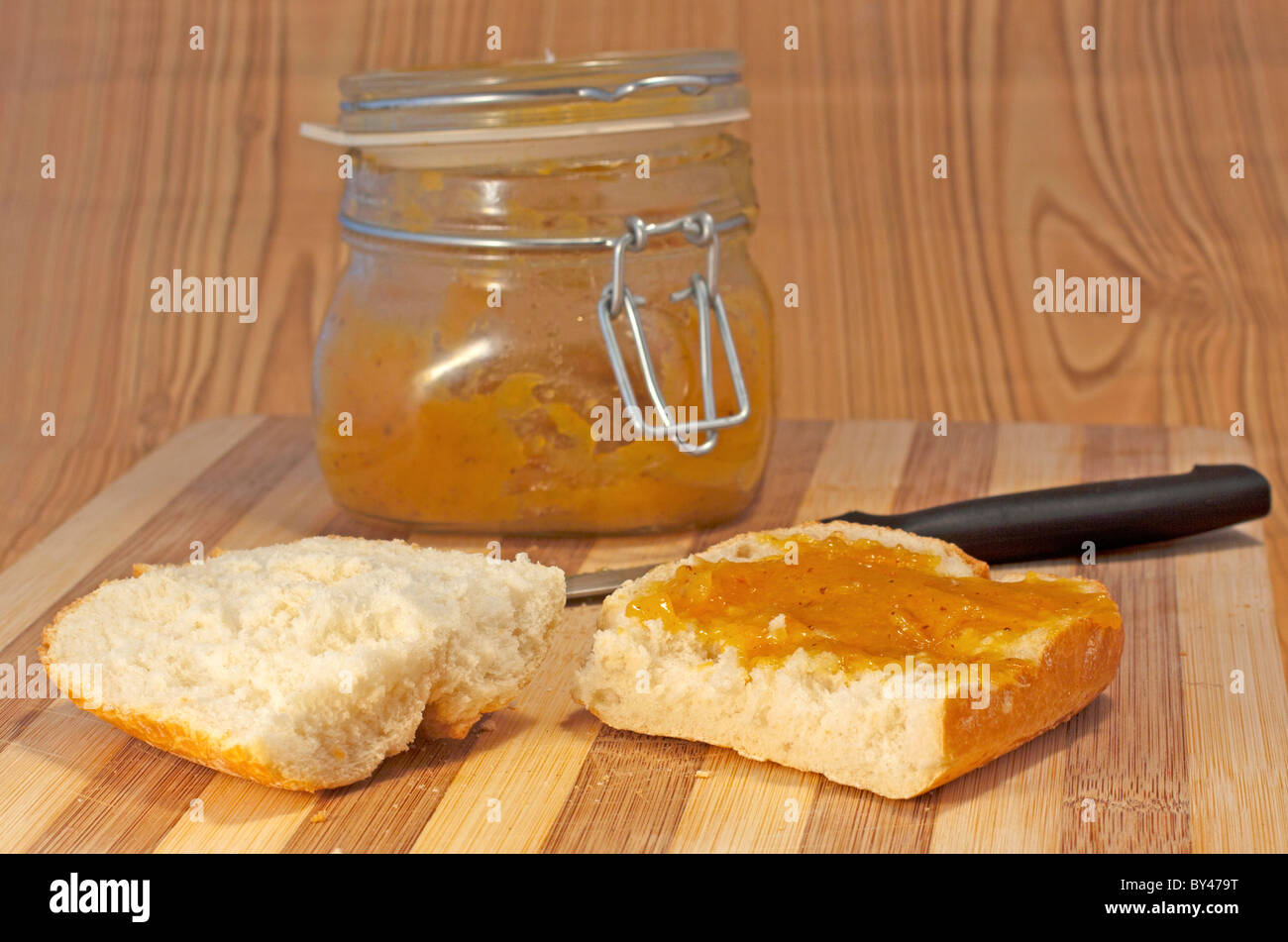 Tagliare il pane con marmellata di colore arancione su sfondo di legno Foto Stock