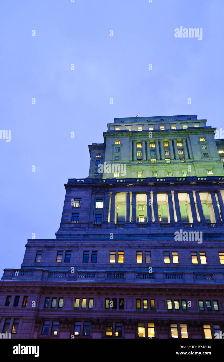 Sun Life Building Montreal al tramonto | MONTREAL, Quebec: I piani superiori del Sun Life Building brillano al crepuscolo sopra il centro di Montreal, con il suo colonnato illuminato e la facciata in pietra che si innalza su René-Lévesque Boulevard. Completato nel 1933, è stato per decenni il più grande edificio dell'Impero britannico per volume, una scala destinata a proiettare il potere finanziario della Sun Life Assurance Company. Foto Stock