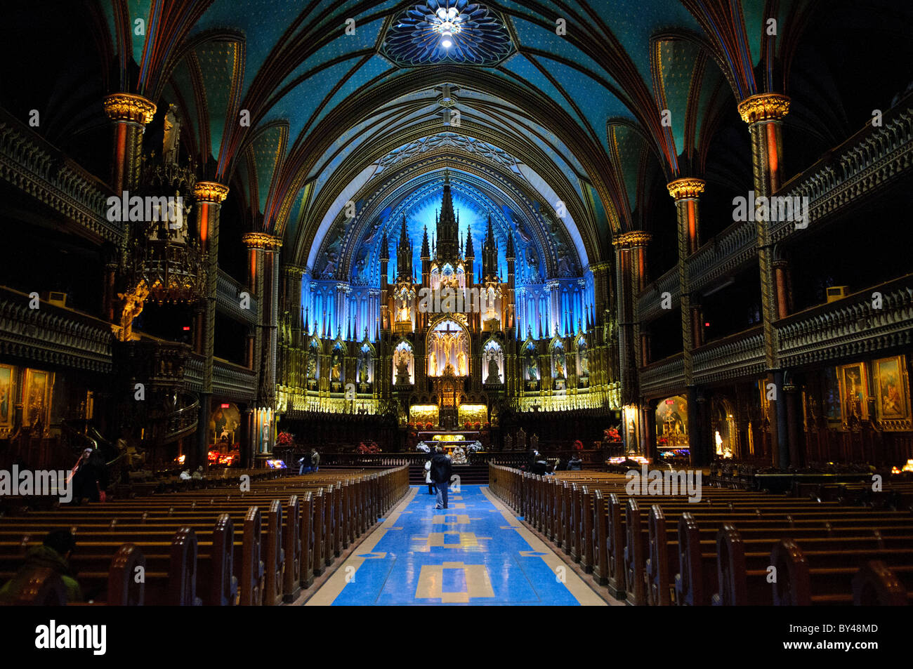Basilica di Notre-Dame Interior Montreal Canada // MONTREAL, Canada - il suggestivo interno della Basilica di Notre-Dame esemplifica il pinnacolo dell'architettura neogotica in Nord America. Completata nel 1840 come la chiesa più grande del continente, la basilica presenta un soffitto a volta blu profondo adornato con stelle dorate, centinaia di intricate sculture in legno e un massiccio organo a canne Casavant Frères con 9.000 canne. L'elaborata decorazione del santuario, progettata da Victor Bourgeau negli anni '1870, combina blu intenso, azzurri, rossi, viola, argento e oro. Foto Stock