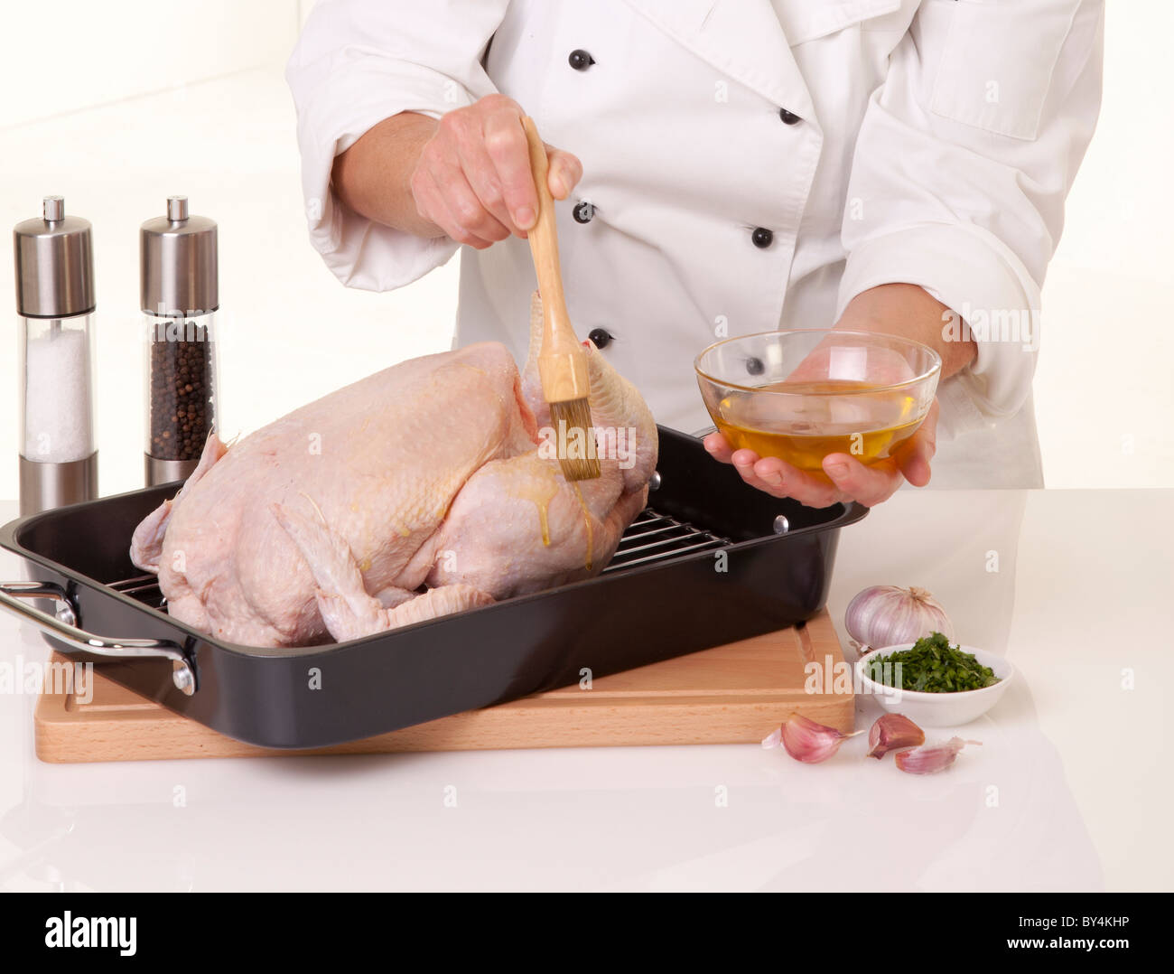 Lo chef prepara il pollo intero per la tostatura,spazzolatura con olio Foto Stock