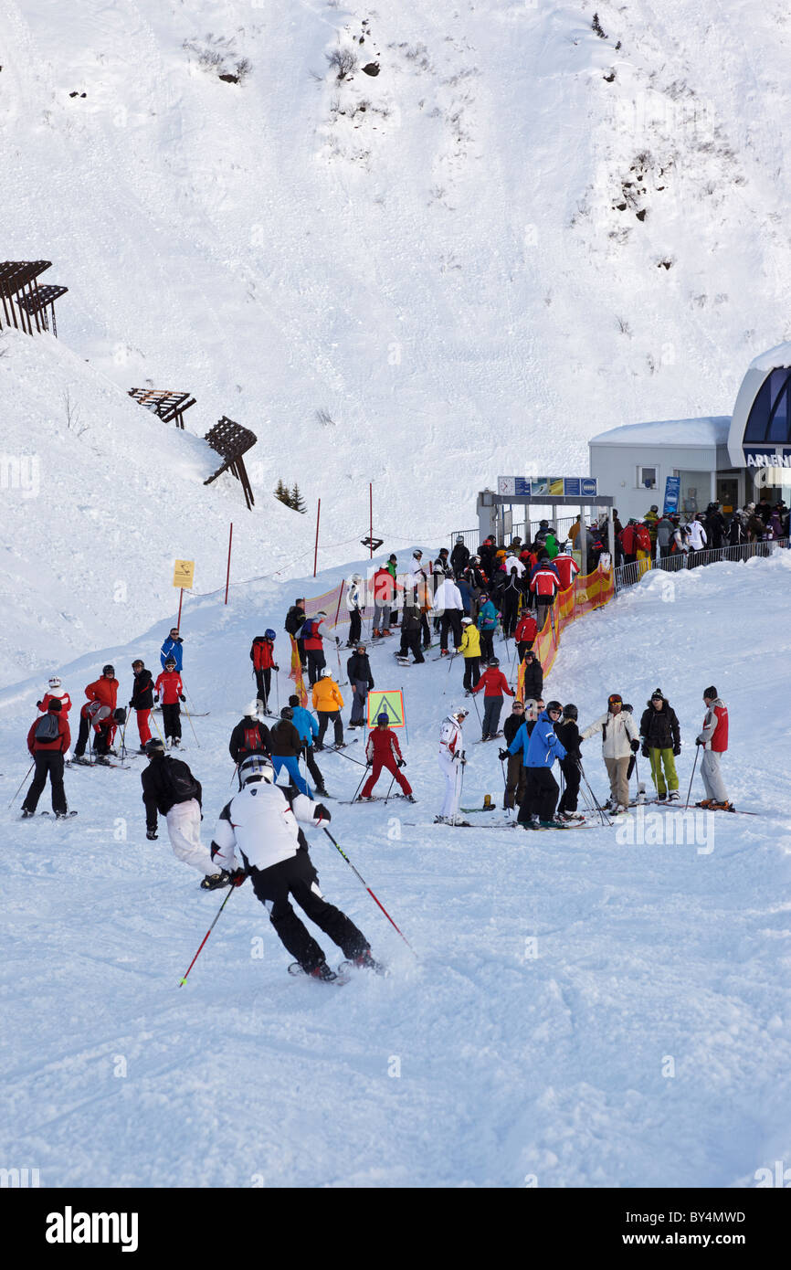 Gli sciatori e gli snowboarder la giunzione di una coda per ottenere sulla seggiovia Arlenmahder in Austrian ski resort di St Anton. Foto Stock