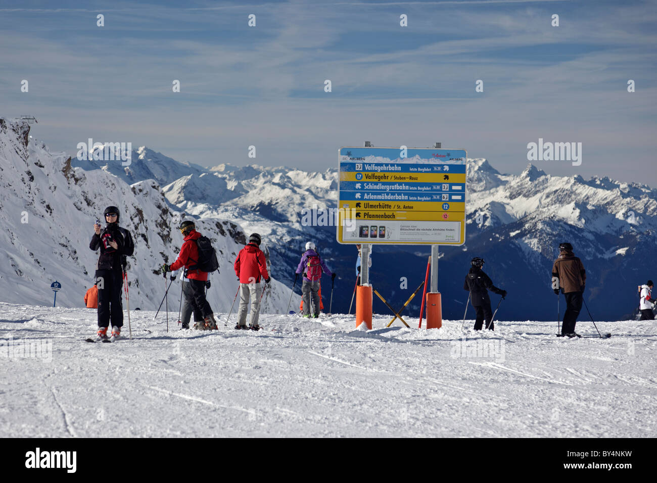 Gli sciatori accanto a una pista di information board nel villaggio austriaco di St Anton Foto Stock