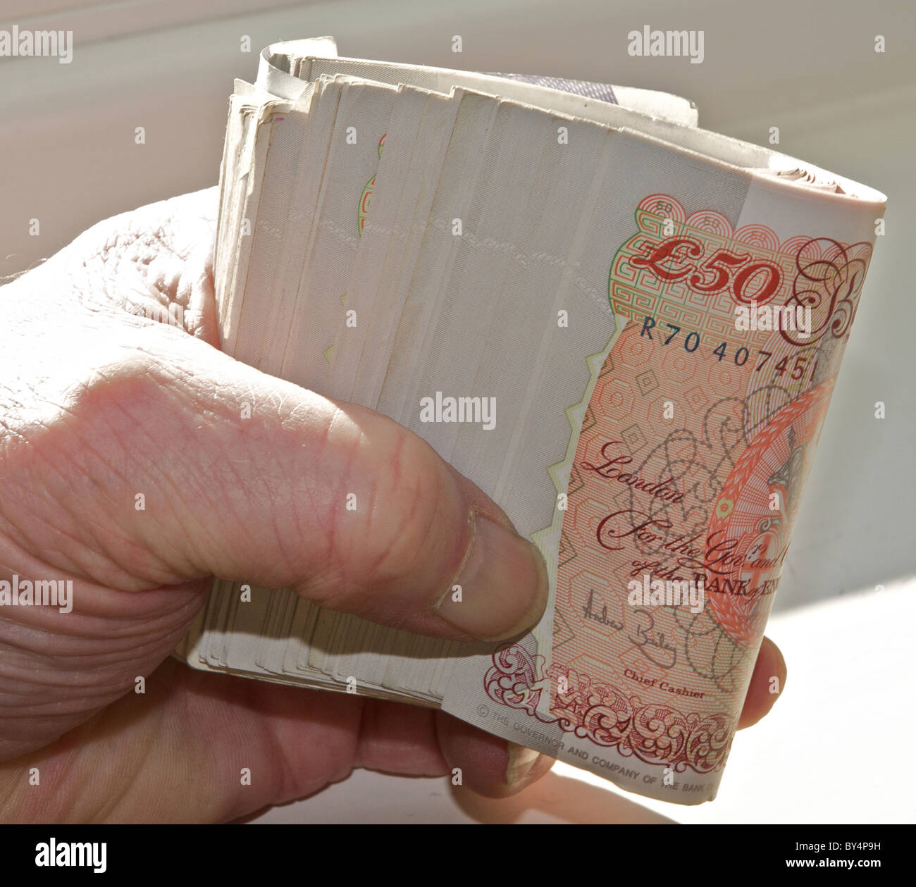 Sterling valuta, un rotolo di UK banconote migliaia di sterline in mano. (Completamente rilasciato - fotografo la propria mano). Dagli archivi di stampa Ritratto Service (ex premere ritratto Bureau) Foto Stock