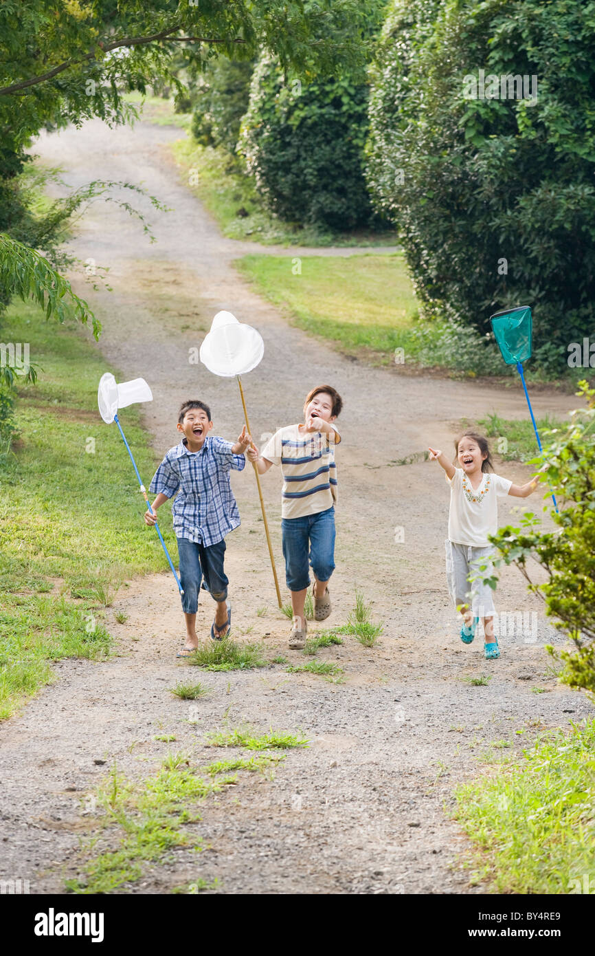 Bambini che correvano con farfalla reti per catturare insetti, nella prefettura di Chiba, Honshu, Giappone Foto Stock