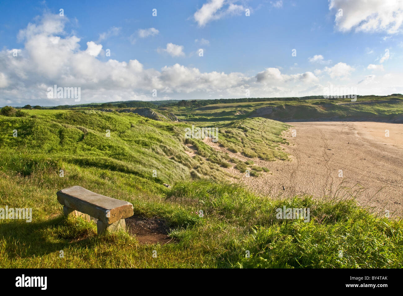 Il sedile in pietra che si affaccia su dune di sabbia e spiaggia di ampia oasi sud, Pembrokeshire. Molto presto la mattina. Foto Stock