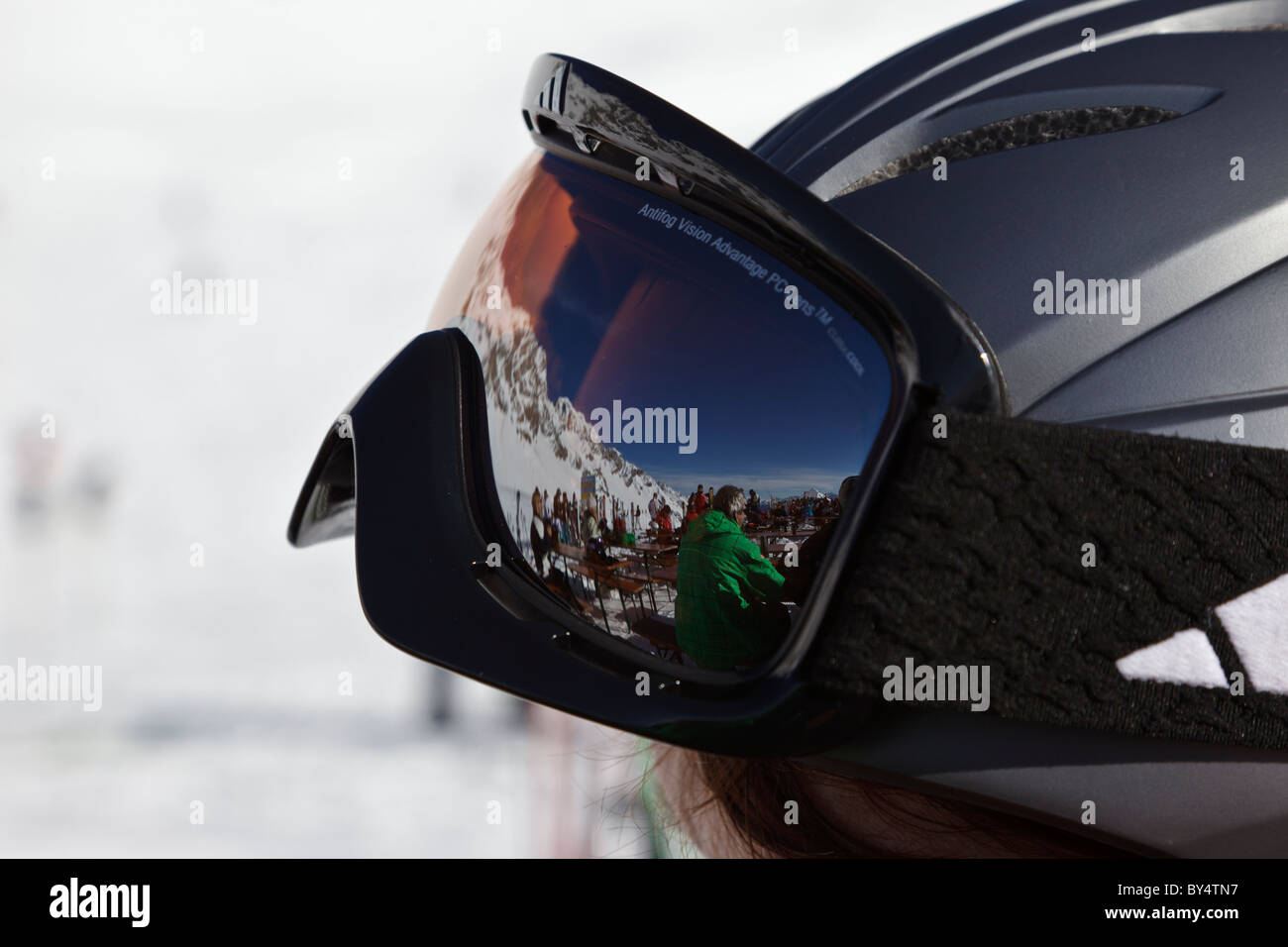 Gli sciatori prendendo una pausa al di fuori di un austriaco ristorante di montagna si riflette in un moderno paio di occhiali di protezione su un casco da sci. Foto Stock