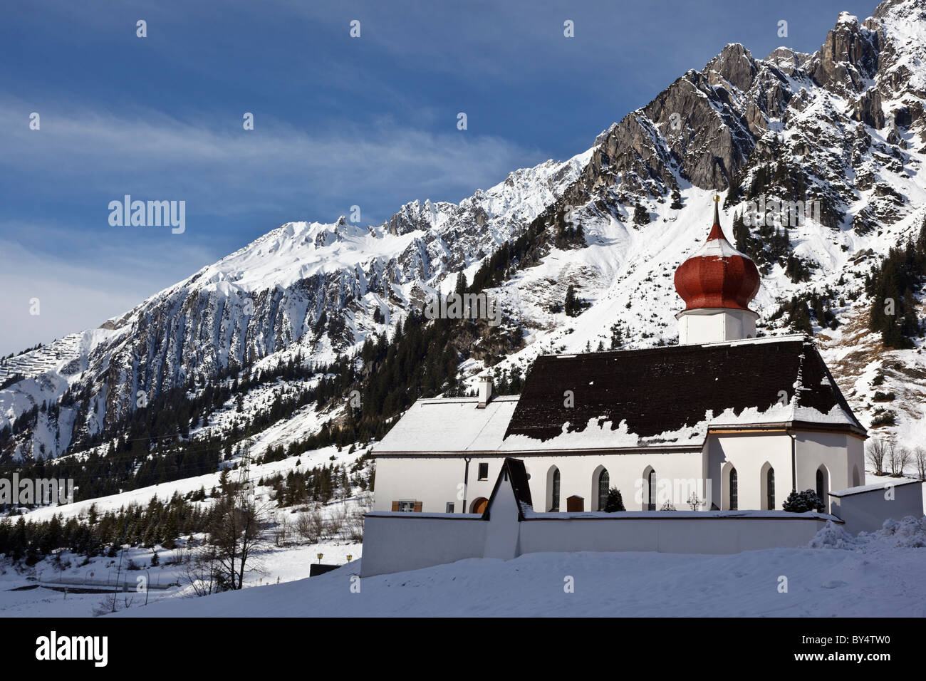 La chiesa a Stuben nell'Alberg ski area contro uno sfondo di montagne coperte di neve. Foto Stock