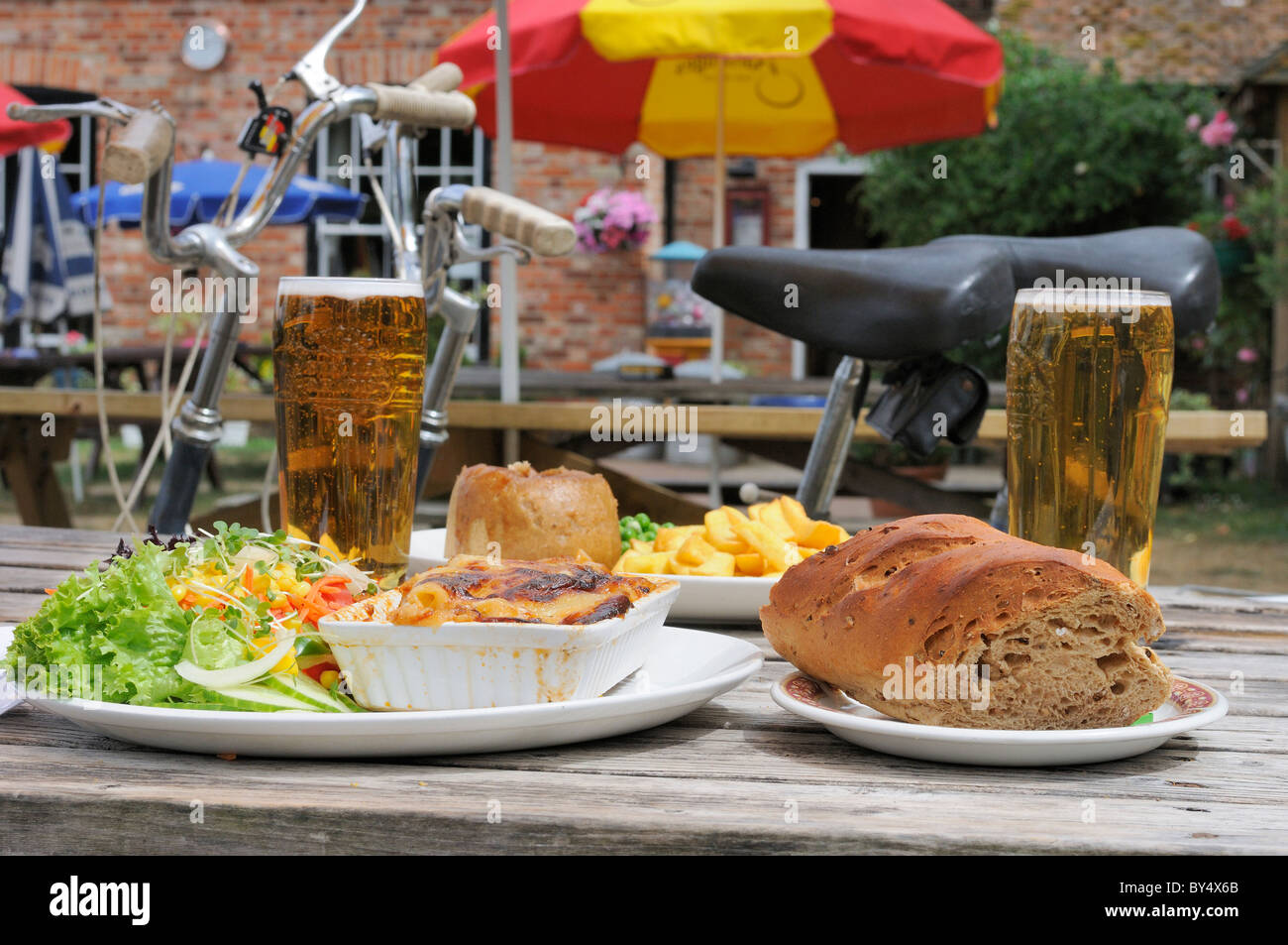 Due ciclisti si fermano per un gustoso pranzo e un po' di lager nel giardino dei pub di campagna del Flower Pot Hotel, Aston, Henley-on-Thames, Berkshire, UK Foto Stock
