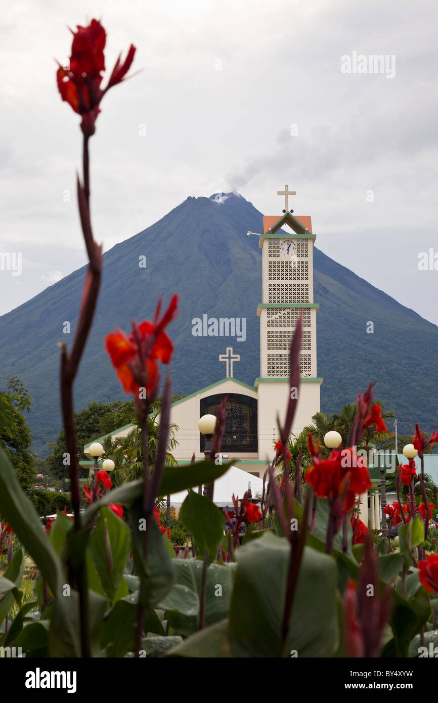 Red Canna Gigli e chiesa in La Fortuna de San Carlos con il Vulcano Arenal in background, Alajuela in Costa Rica. Foto Stock