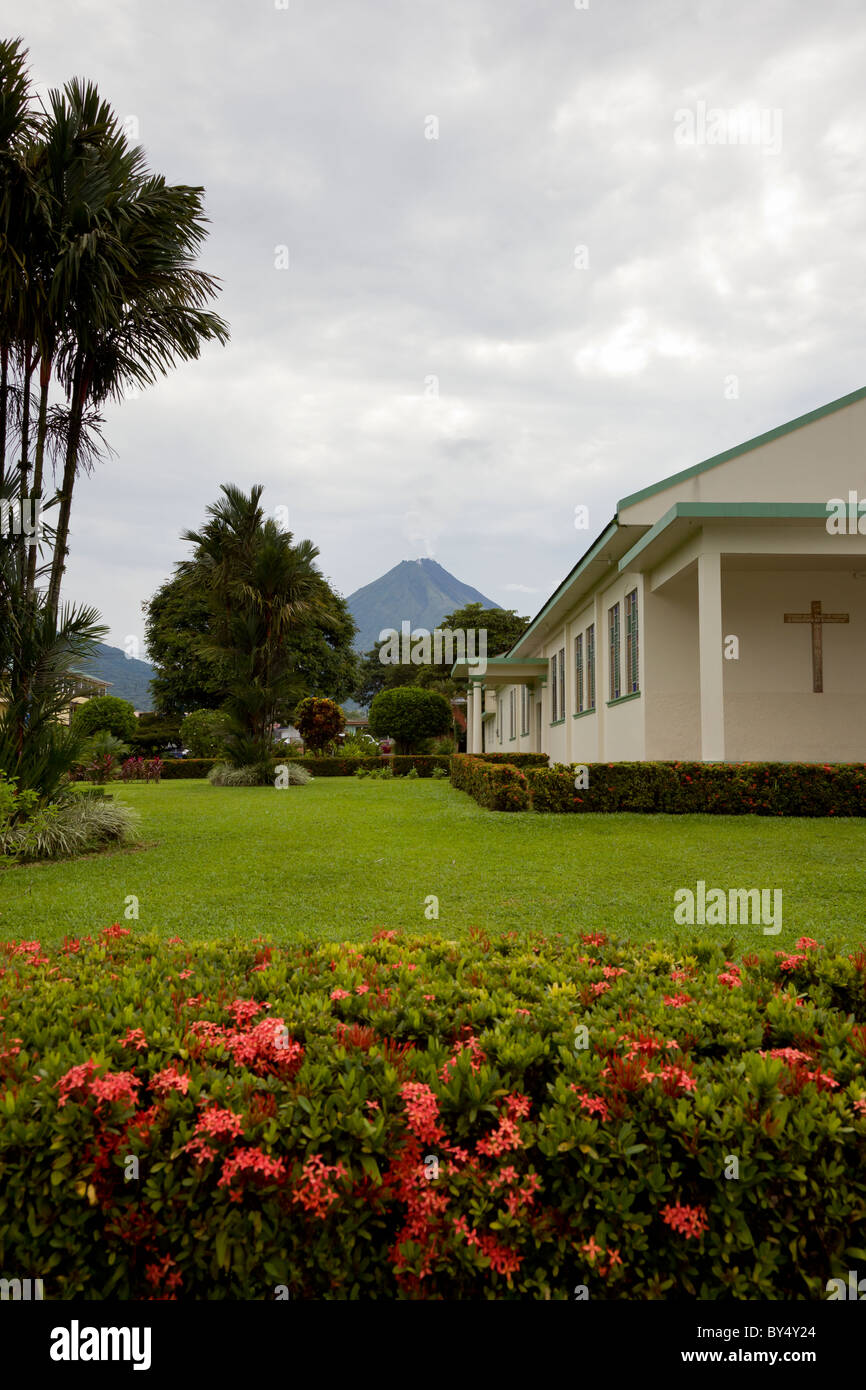 La Parroquia San Juan Bosco chiesa in La Fortuna de San Carlos con il Vulcano Arenal incombente in background, Costa Rica. Foto Stock