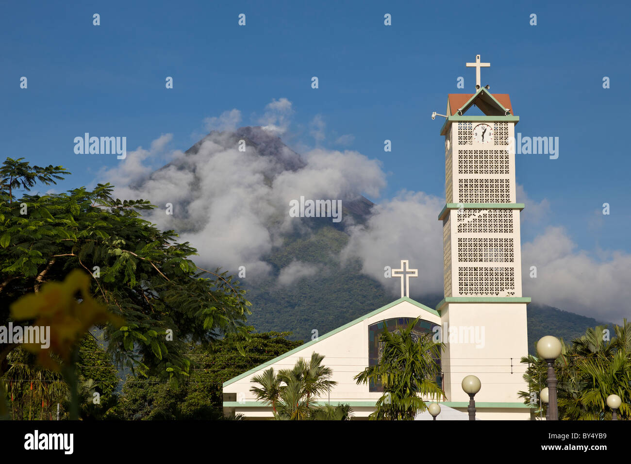 Le nubi oscure che si profila il Vulcano Arenal dietro la centrale Chiesa chiesa in La Fortuna de San Carlos, Alajuela in Costa Rica. Foto Stock