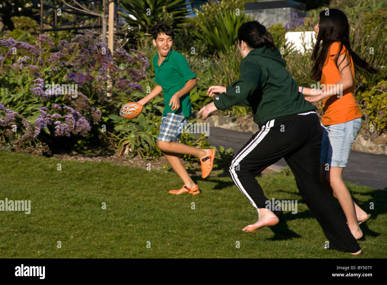 Due Asiatico-americano teenage sorelle giocare a toccare il calcio con il loro fratello nel sole del pomeriggio in Laguna Beach, CA. Modello di rilascio Foto Stock