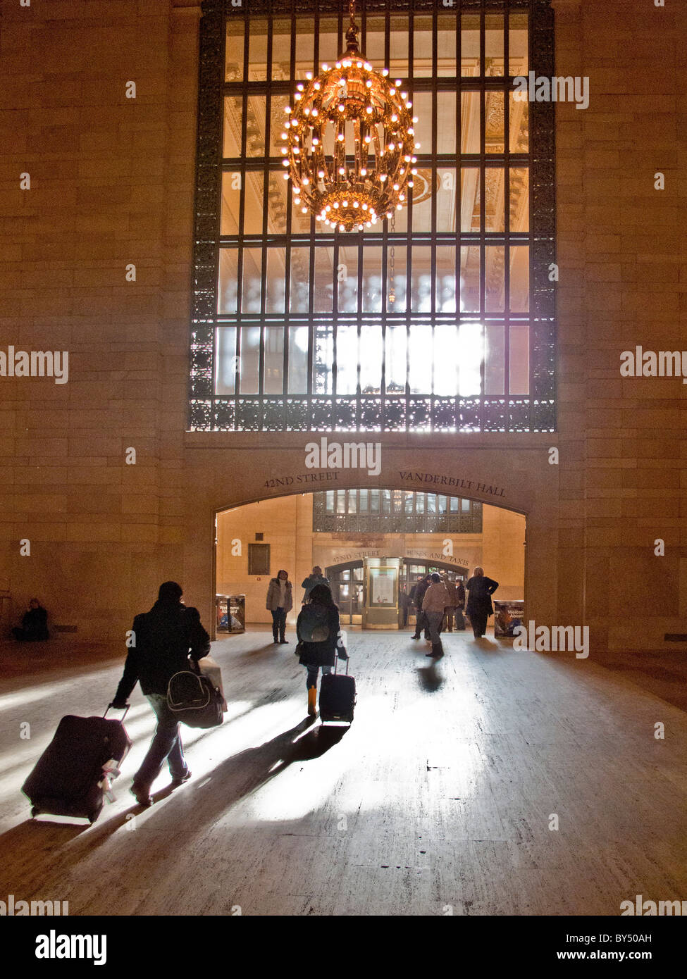 Nel sole del pomeriggio, i viaggiatori con bagaglio la testa per la 42nd Street uscita della Grand Central Station nel centro cittadino di Manhattan, New York C Foto Stock