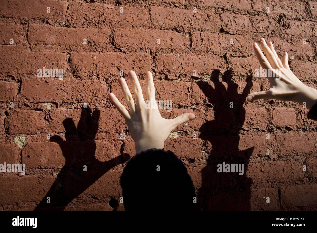 Mani e ombre su un muro di mattoni in inverno la luce. Foto Stock