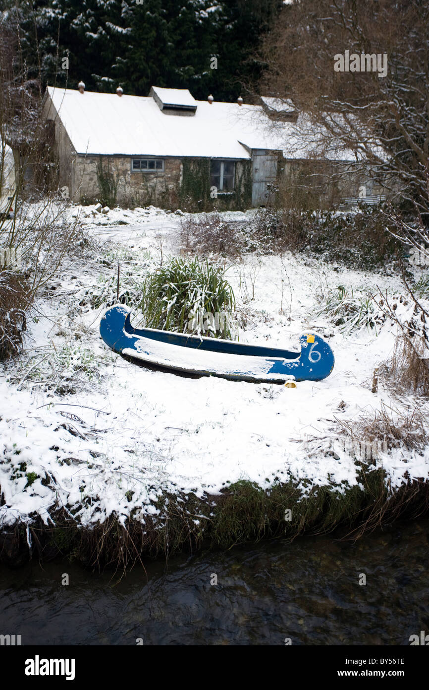 Un kayak siede sulla coperta di neve banca del fiume di Gweek, Cornwall. Foto Stock