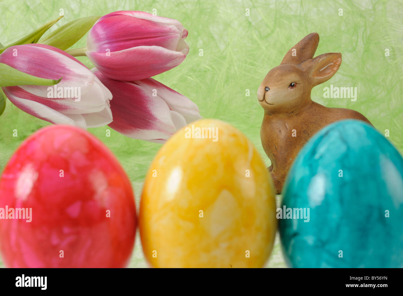 Coniglietto di Pasqua con i tulipani e il rosso, il verde e il giallo uovo Foto Stock