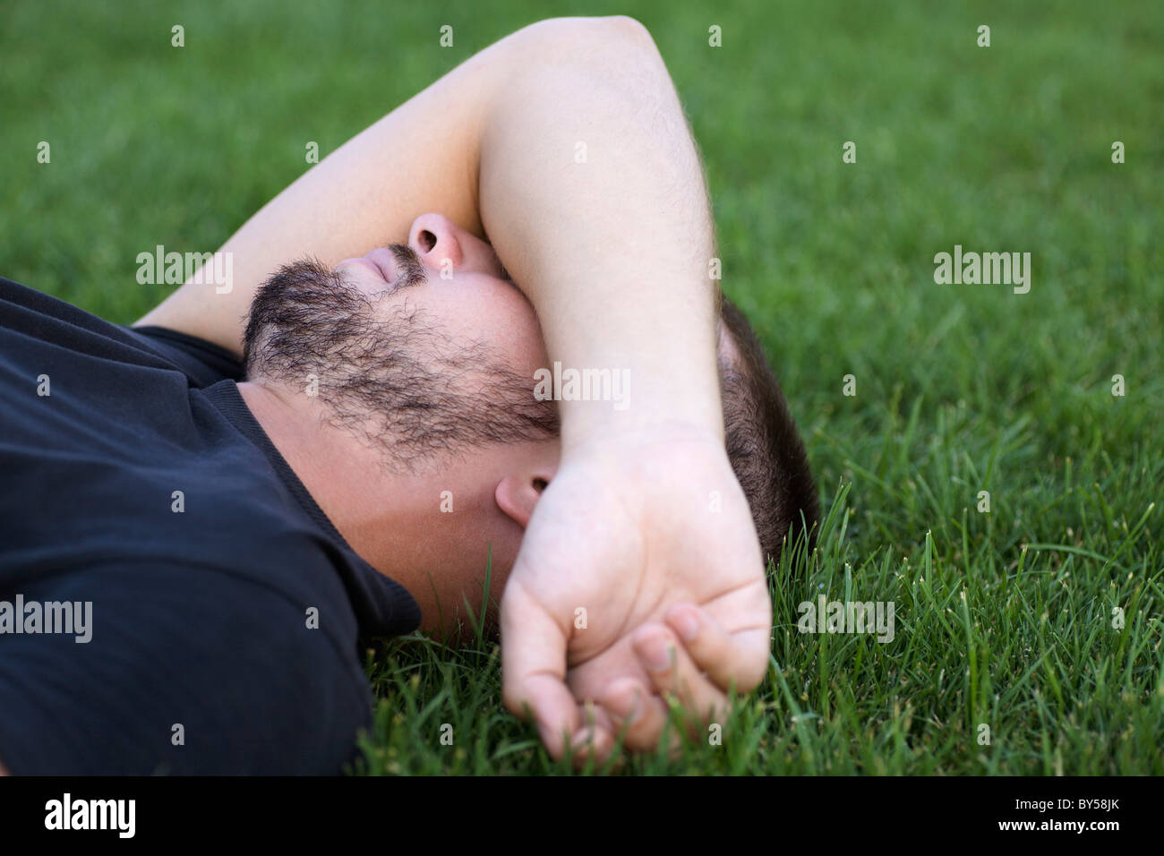 Close-up uomo posa sul braccio di erba sulla faccia Foto Stock