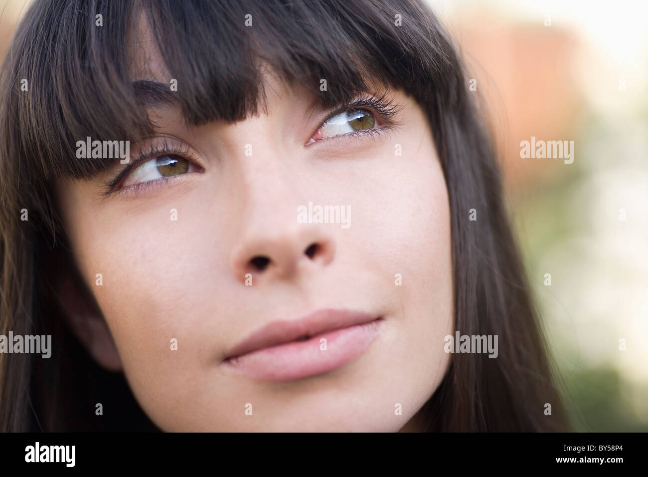 Una giovane donna che guarda verso l'alto, la messa a fuoco sulla faccia Foto Stock