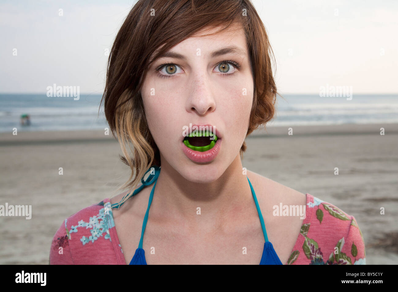 Una donna che indossa i denti del vampiro in spiaggia, ritratto Foto Stock