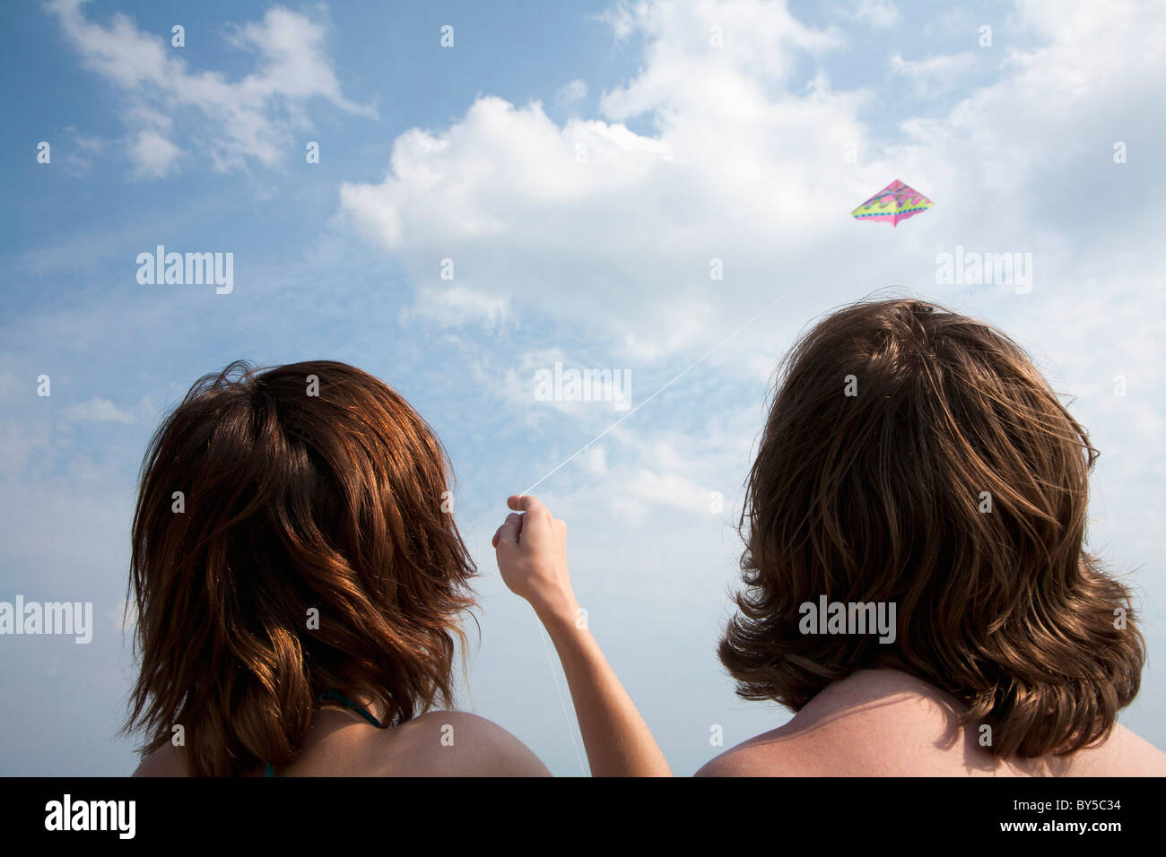 Una giovane coppia volare un aquilone, vista posteriore Foto Stock