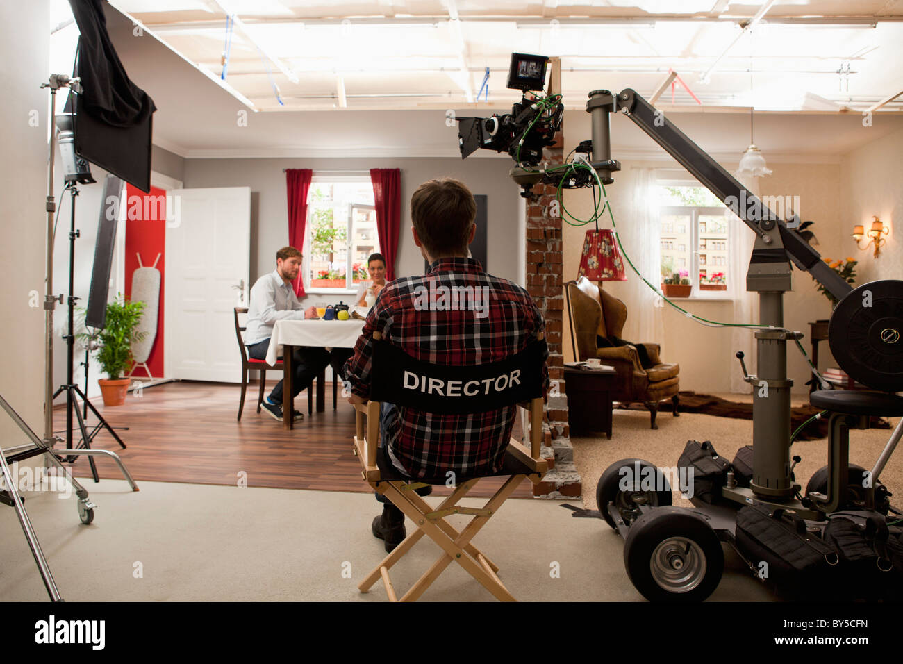 Un direttore su un set cinematografico guardando gli attori eseguire una scena Foto Stock