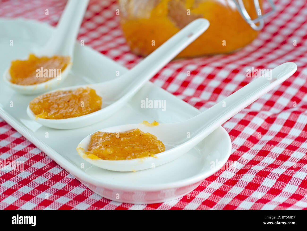Inceppamento arancione su bianco cucchiai, con vaso sullo sfondo Foto Stock