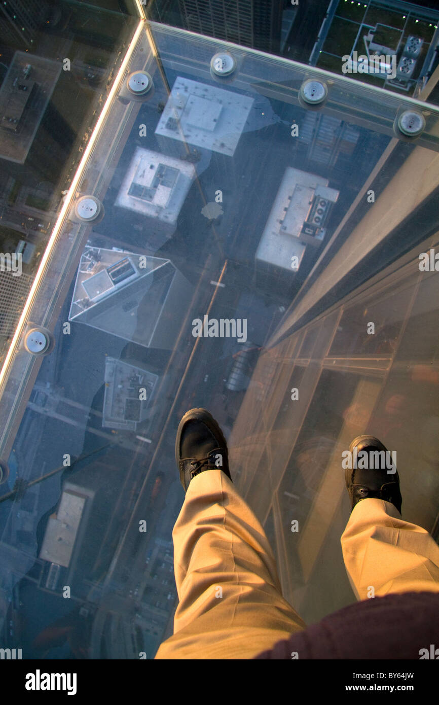 Un uomo con i piedi sul lo skydeck della Willis Tower a Chicago, Illinois, Stati Uniti d'America. Foto Stock