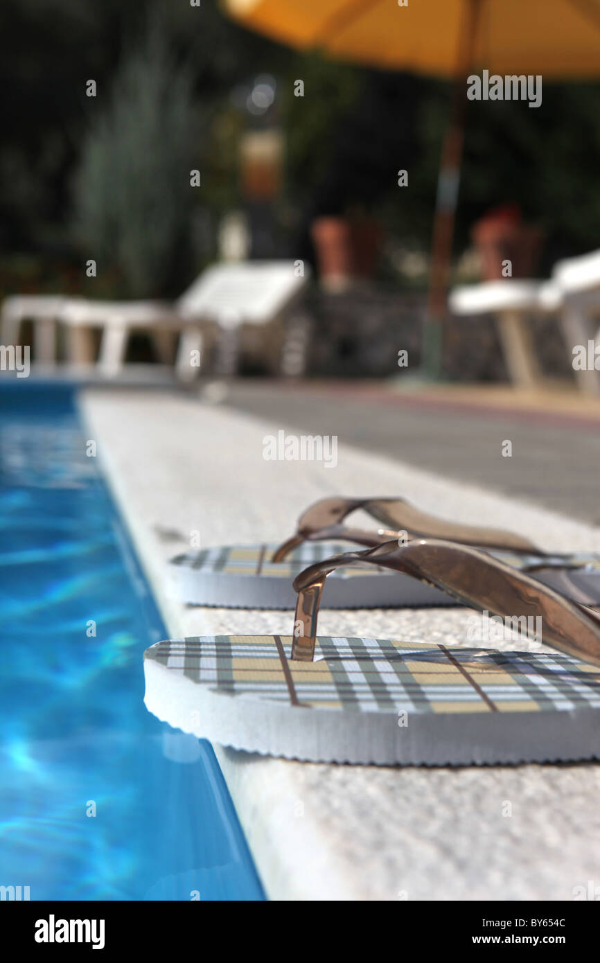 Coppia di flip flop posto in corrispondenza del bordo di una piscina Foto Stock