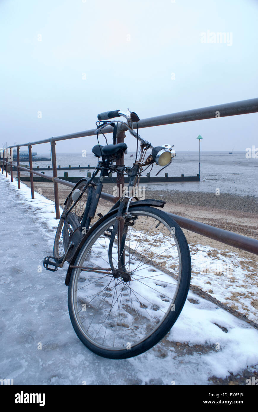 Bicicletta appoggiata contro le ringhiere dal mare nevoso Foto Stock