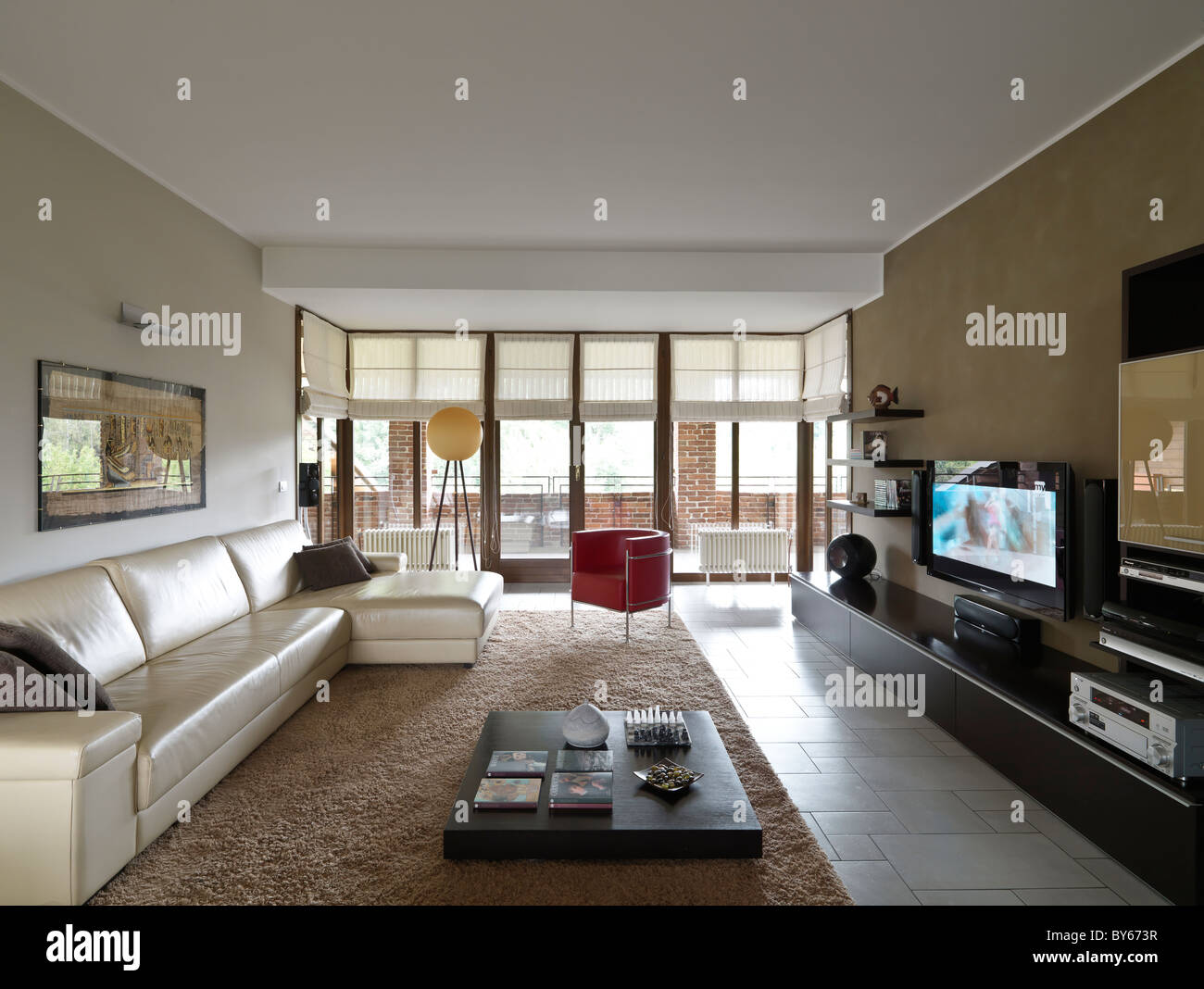 Soggiorno moderno con uno stile contemporaneo e un divano e poltrona in pelle di colore beige e rosso Foto Stock