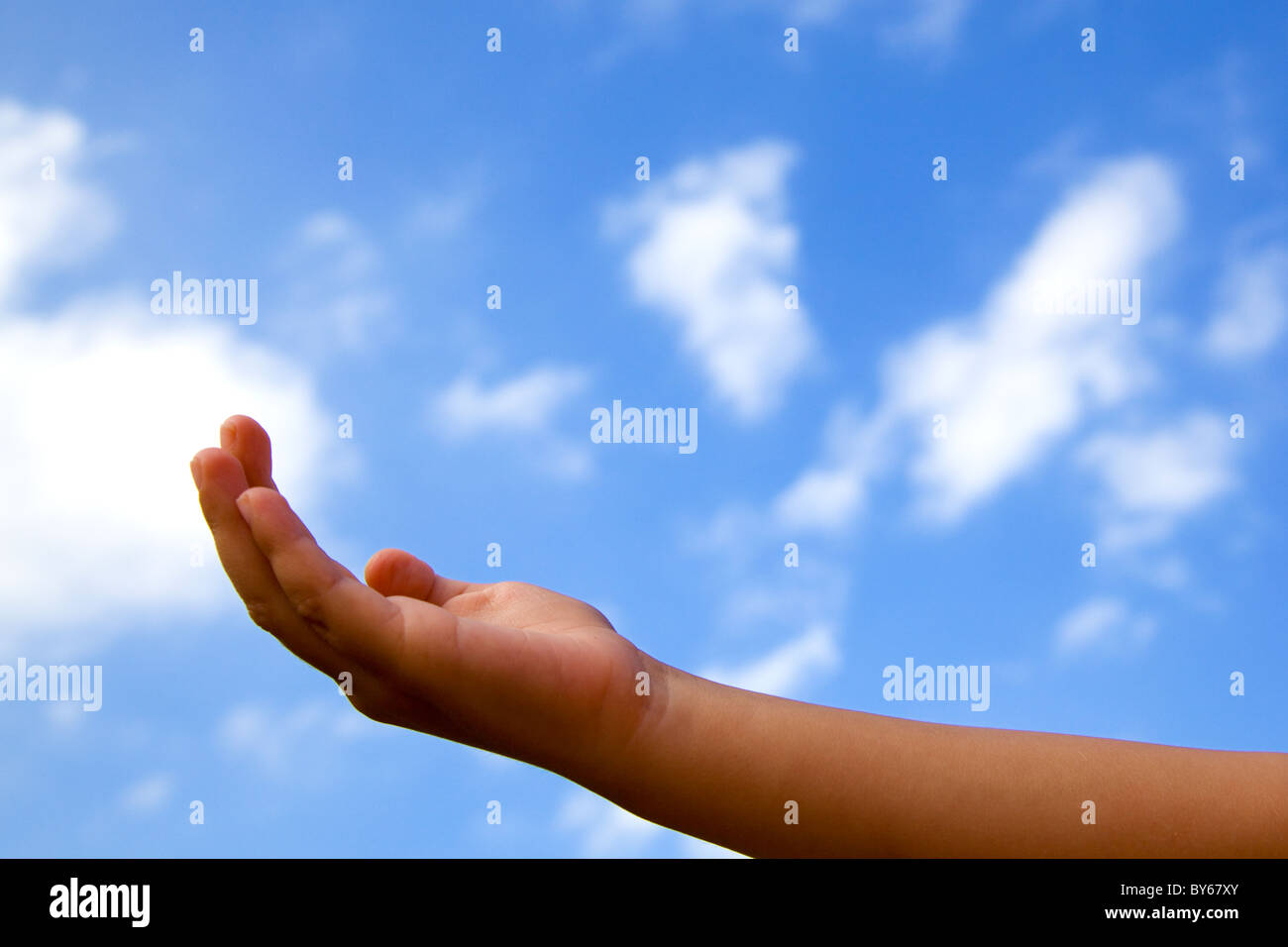 Aprire la mano di un bambino contro un nuvoloso cielo blu Foto Stock