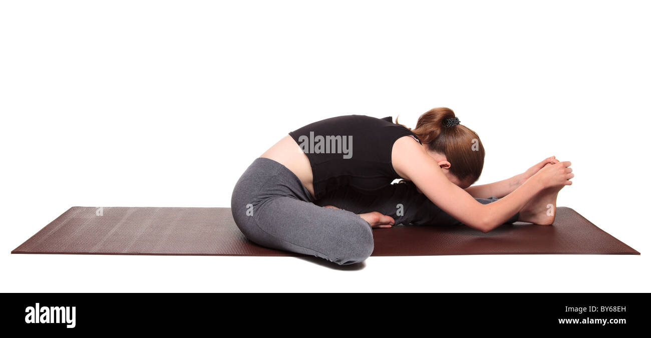 Isolato studio shot di montare una donna caucasica tenendo la janu sirsasana testa a ginocchio posizione di yoga su un esercizio mat. Foto Stock