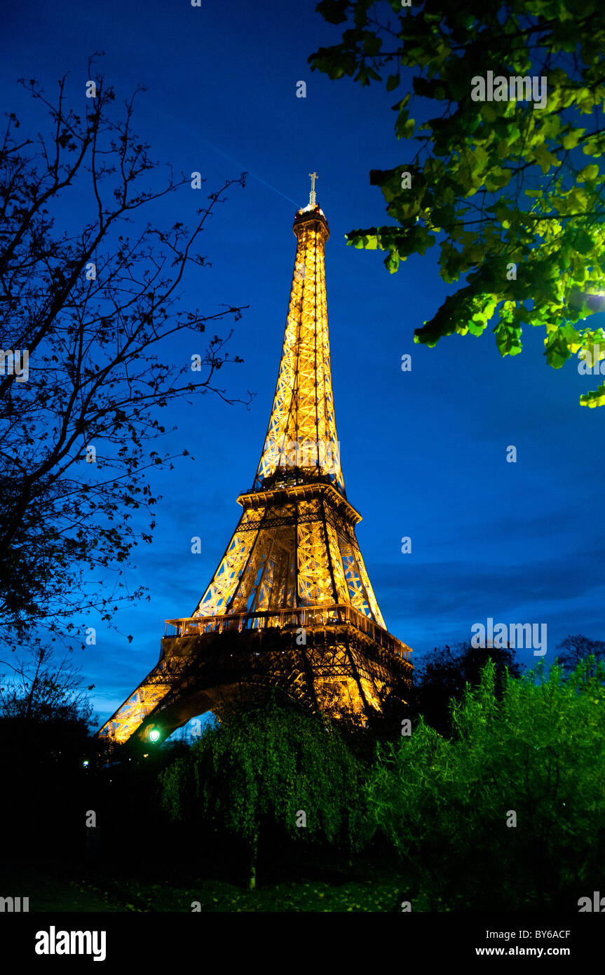 Luci dorate illuminate dalla Torre Eiffel di notte Parigi Francia // PARIGI, Francia - la Torre Eiffel è illuminata con luci dorate contro il cielo notturno di Parigi, Francia. Questa iconica torre a reticolo di ferro, situata sul campo di Marte, è stata progettata dall'azienda Gustave Eiffel per l'esposizione universale del 1889. Alto 330 metri (1.083 piedi) con la sua antenna, è un punto di riferimento importante nella capitale francese. Il suo brillante display crea un faro nel paesaggio notturno parigino. La torre è un'icona culturale globale e un simbolo della Francia. Foto Stock