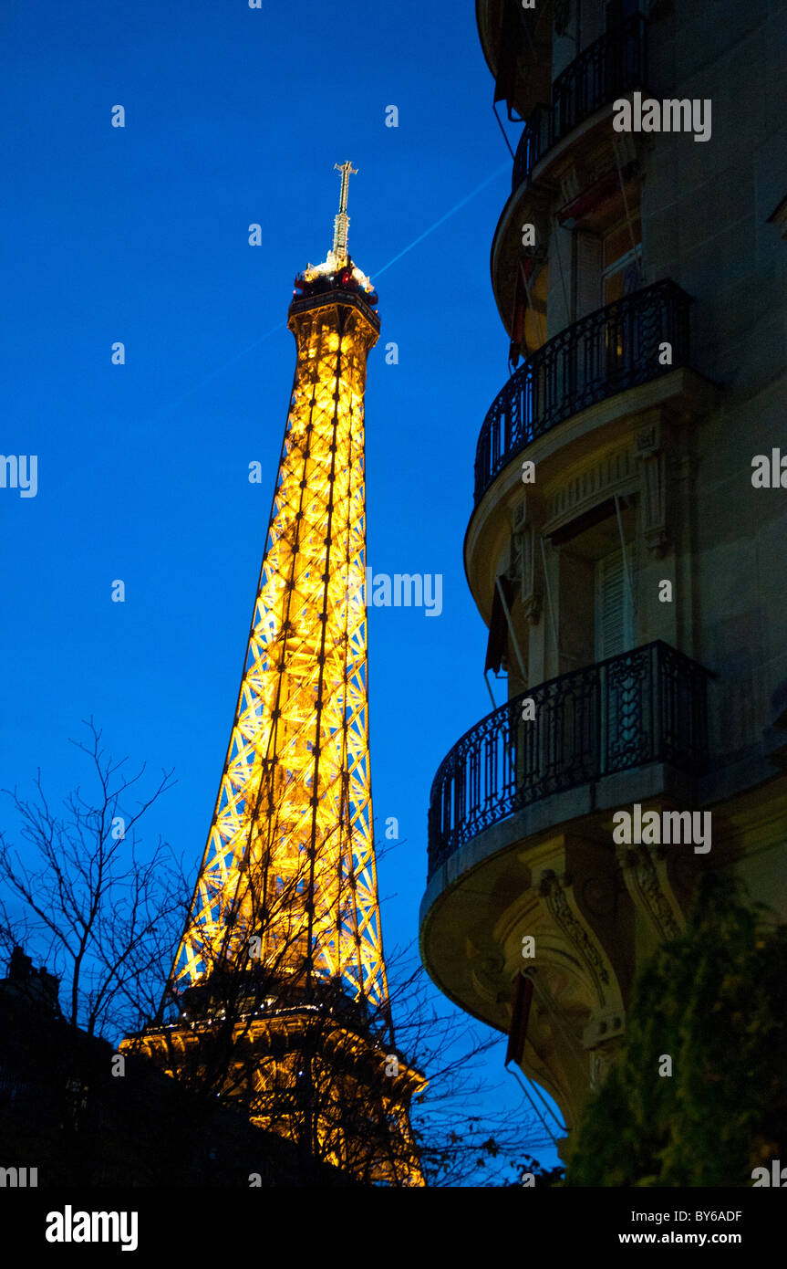 Torre Eiffel struttura in ferro illuminata luci d'oro Searchlight Parigi Francia // PARIGI, Francia - la Torre Eiffel, un'iconica struttura a reticolo di ferro, è illuminata da luci dorate e da uno scintillante display, con un fascio di luce mirata contro il cielo notturno. Faro nel paesaggio notturno parigino, è stato progettato da Gustave Eiffel per l'esposizione universale del 1889. La torre è alta 330 metri (1.083 piedi), inclusa l'antenna. Situato sul Champ de Mars a Parigi, Ile-de-France, è un'icona culturale globale della Francia. È uno dei monumenti a pagamento più visitati al mondo. Foto Stock