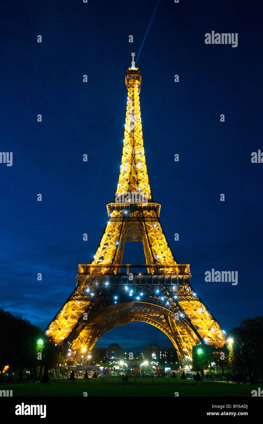 Torre Eiffel illuminata con fascio di luce di ricerca Parigi Francia // PARIGI, Francia - la Torre Eiffel è illuminata di notte con luci dorate e un'esposizione scintillante, con un prominente fascio di luce di ricerca dalla sua cima. Questa iconica torre reticolare in ferro battuto sul campo di Marte è un'icona culturale globale della Francia. Progettato da Gustave Eiffel, è stato costruito dal 1887 al 1889 per l'esposizione universale del 1889. Con un'altezza di 330 metri (1.083 piedi), inclusa la sua antenna, è stata la struttura artificiale più alta del mondo per 41 anni. Il suo spettacolo di luci notturne e il faro rotante trasformano la notte parigina Foto Stock