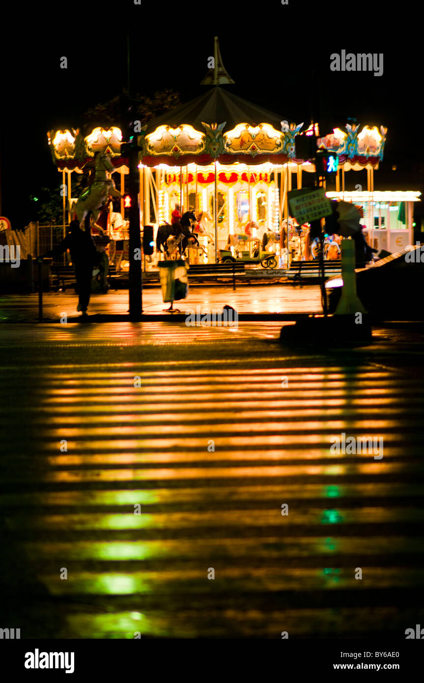 Torre Eiffel Carousel Lights Reflection Wet Zebra Crossing Paris France // PARIS, France - luci da una giostra tradizionale, con il "Jardin de Paris" sui suoi pannelli, riflettono su un'umida traversata pedonale zebra vicino alla Torre Eiffel. La vivace illuminazione della giostra crea un'incredibile luce sul pavimento bagnato. Le giostre sono una vista comune e amata a Parigi, spesso situata vicino ai principali luoghi di interesse come la Torre Eiffel. Queste attrazioni classiche contribuiscono all'iconico ambiente notturno della città. I riflessi evidenziano l'interazione dinamica della luce e dell'ambiente urbano in t Foto Stock